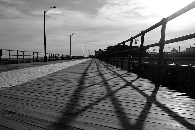 Boardwalk railing throwing hard diagonal shadows across the deck