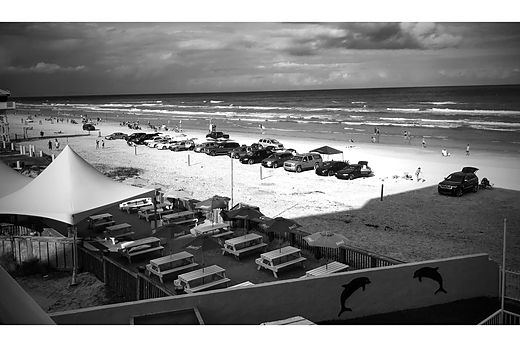 Beachfront cabanas and parked cars, printed with a white border