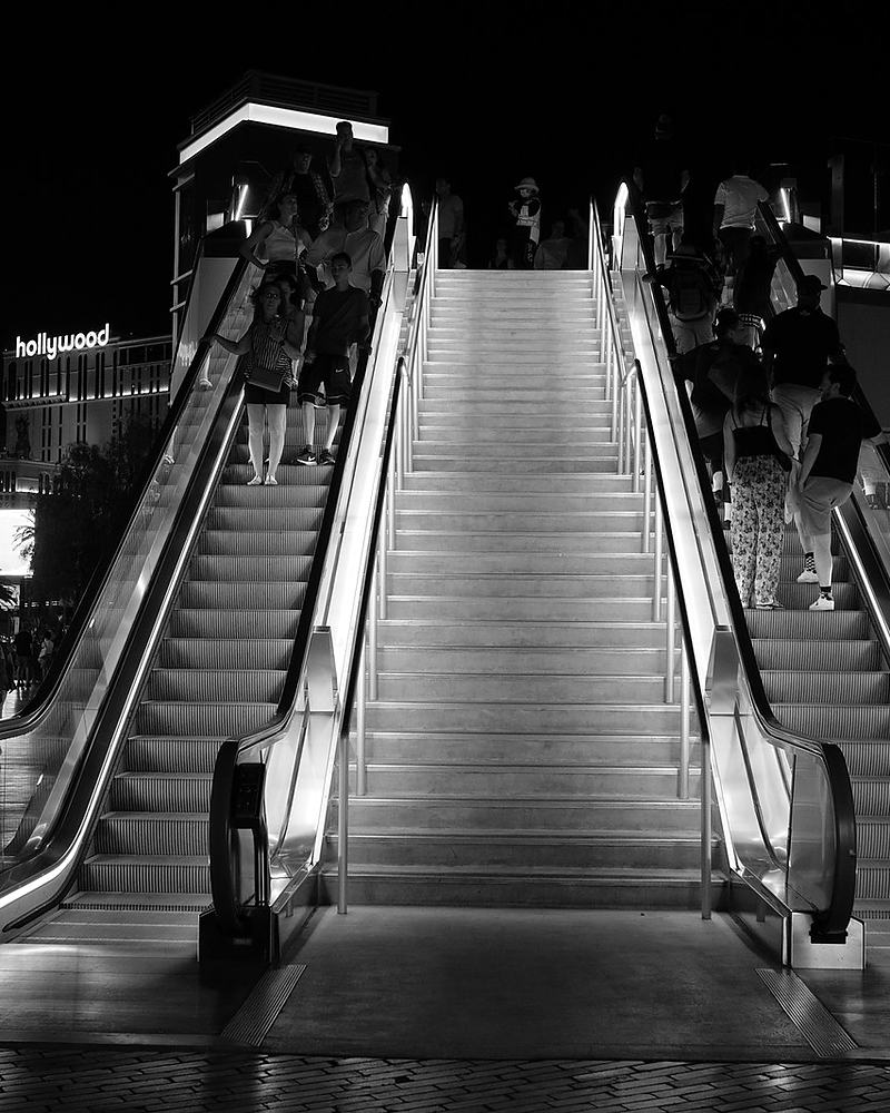 Black and white escalators at night, converging metal diagonals