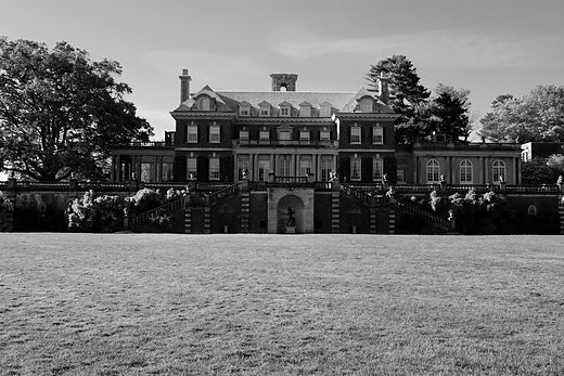Large country house across a wide lawn, black and white