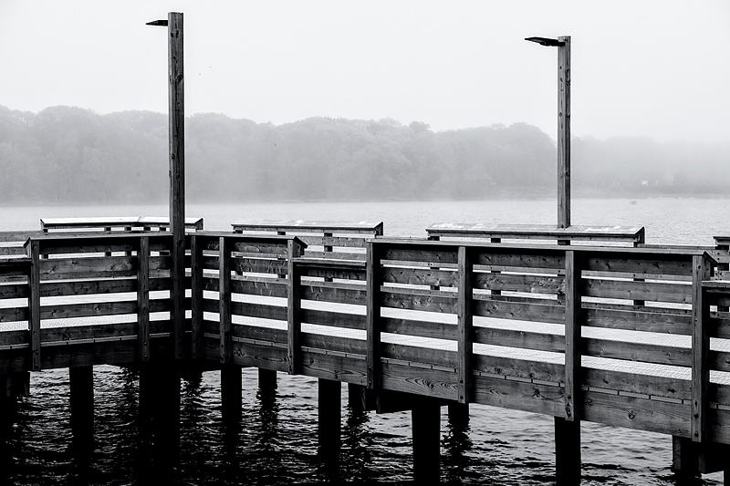 Empty timber pier and lamp standards fading into river fog