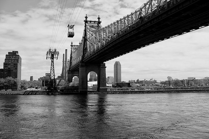 Cantilever bridge in black and white with the skyline stacked behind it