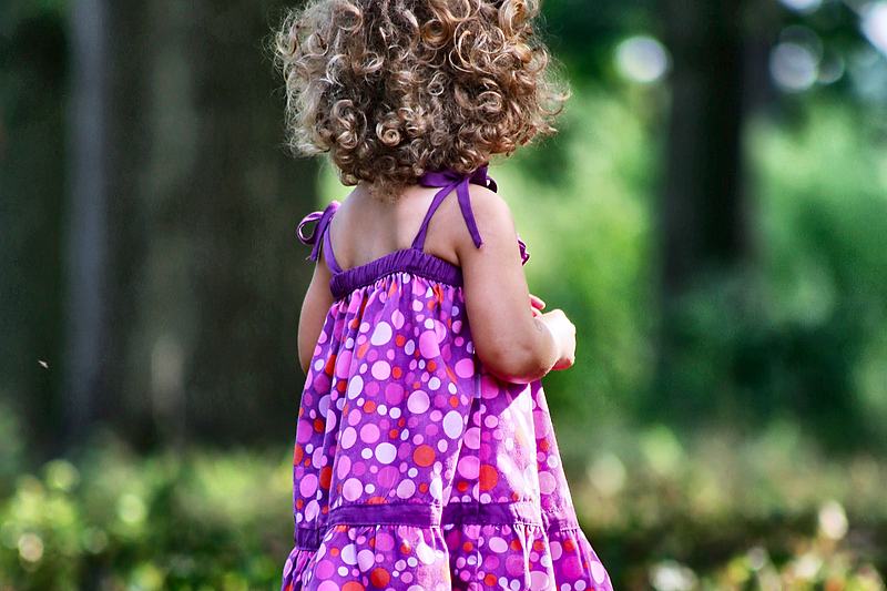 Small child in a purple dress in dappled light