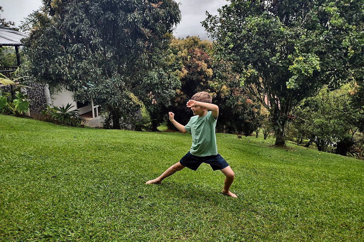Child caught mid-run across a lawn, arms out