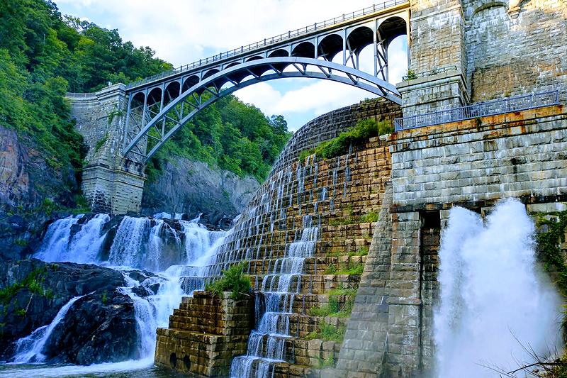 Stone arch bridge above a spillway in full flow
