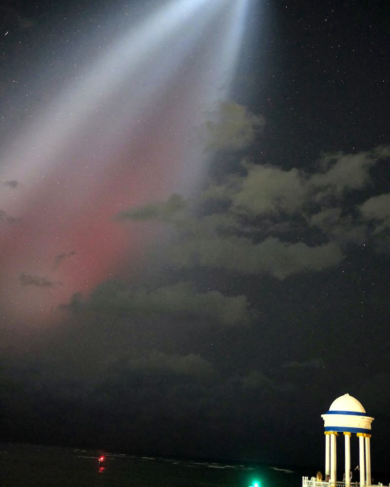 Searchlight beam thrown over a waterfront gazebo at night