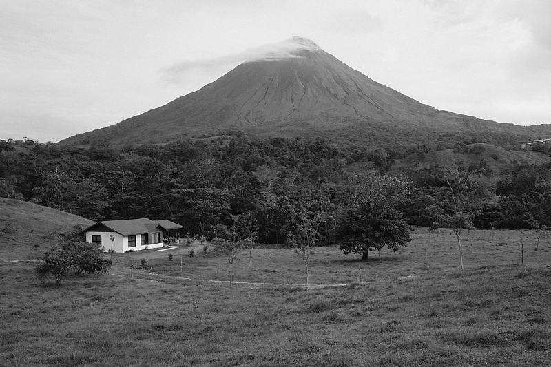 Black and white volcano standing above a small farm