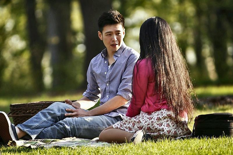 Two young people sitting together on the grass in late afternoon light
