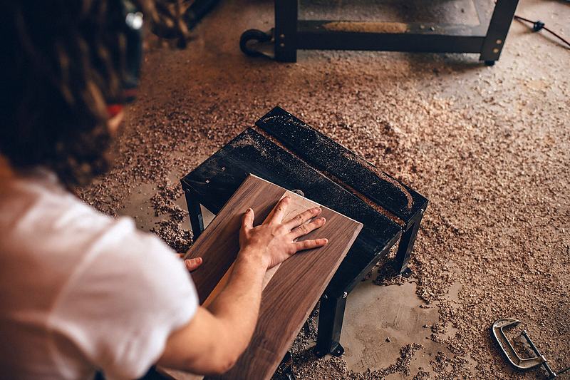 Reference frame: hands working a piece of material on a workshop bench