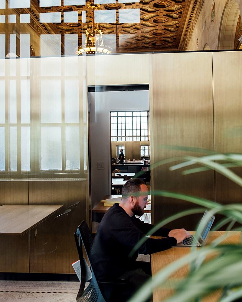 Reference frame: a person working at a long table in a daylit office