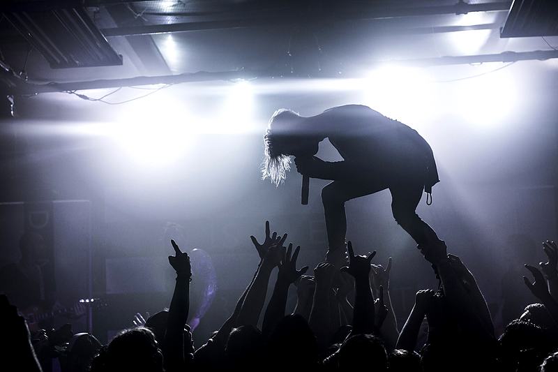 Reference frame: performer silhouetted against stage lights above a crowd