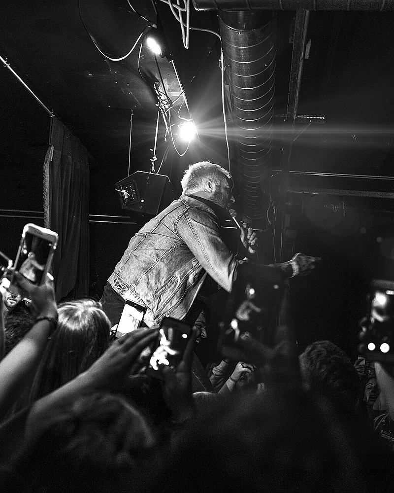 Reference frame: black and white singer at the front of a small stage