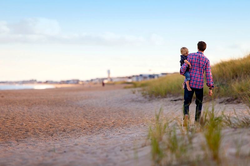 Reference frame: a parent carrying a child along a wide empty beach