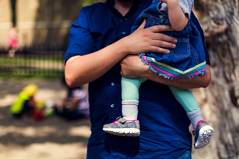 Reference frame: a parent carrying a toddler, close and candid