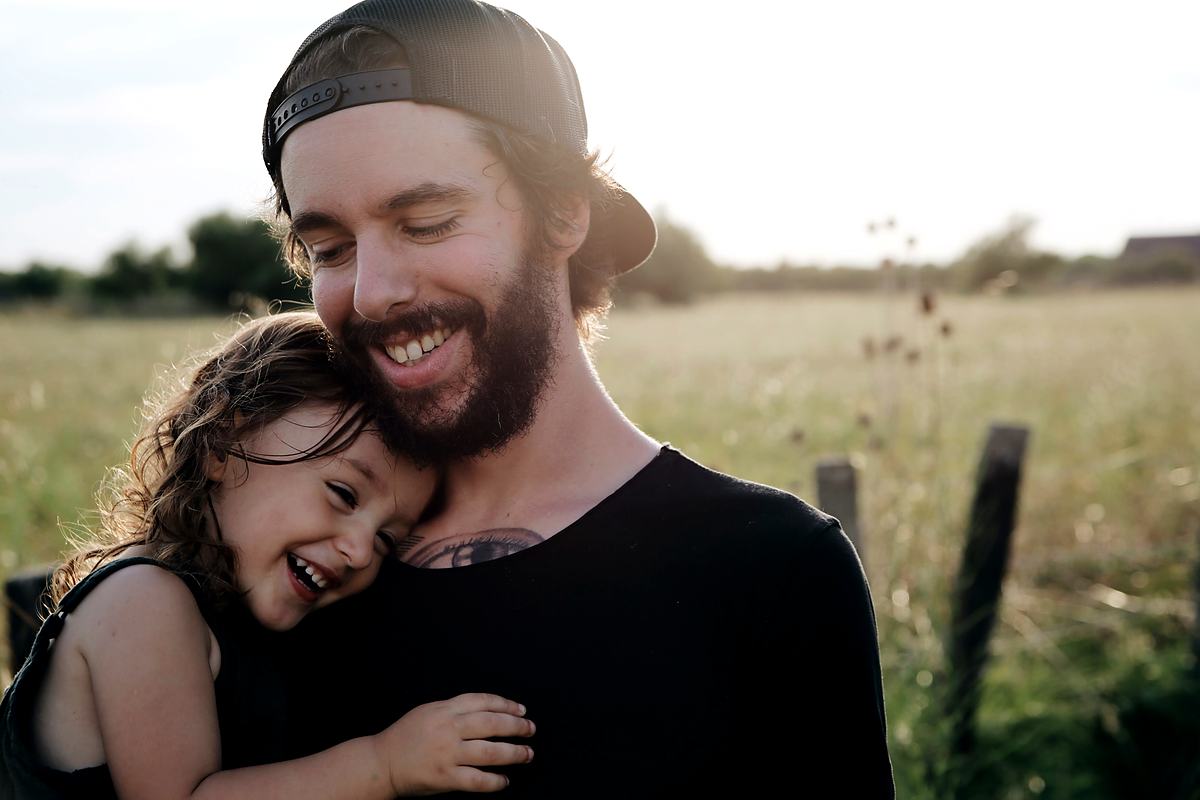 Reference frame: a father holding a laughing child up in a field
