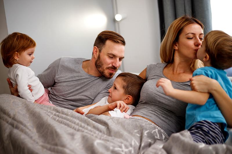 Reference frame: parents and children together in bed with a newborn