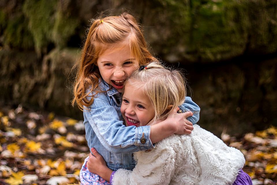 Reference frame: two girls laughing with their arms around each other among autumn leaves