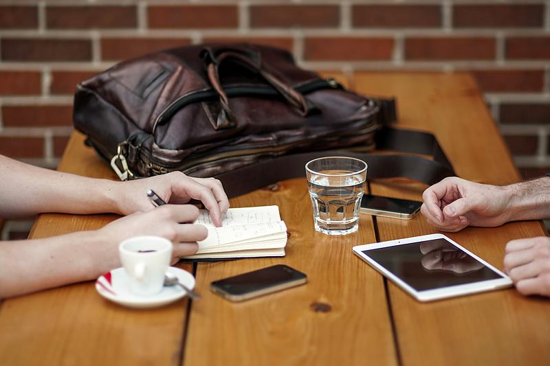 Reference frame: two people in conversation across a table of notebooks