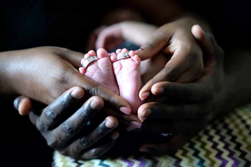 Reference frame: newborn feet cupped in a parent's hands