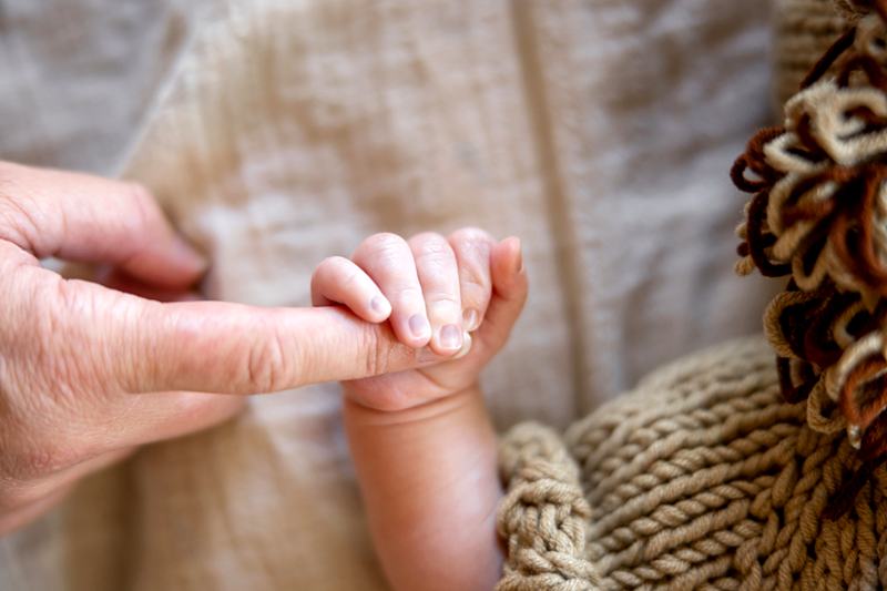 Reference frame: a newborn's fingers closed around an adult finger