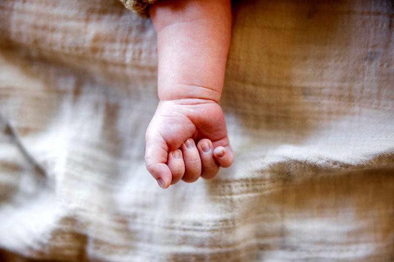 Reference frame: a newborn's hand curled on soft muslin