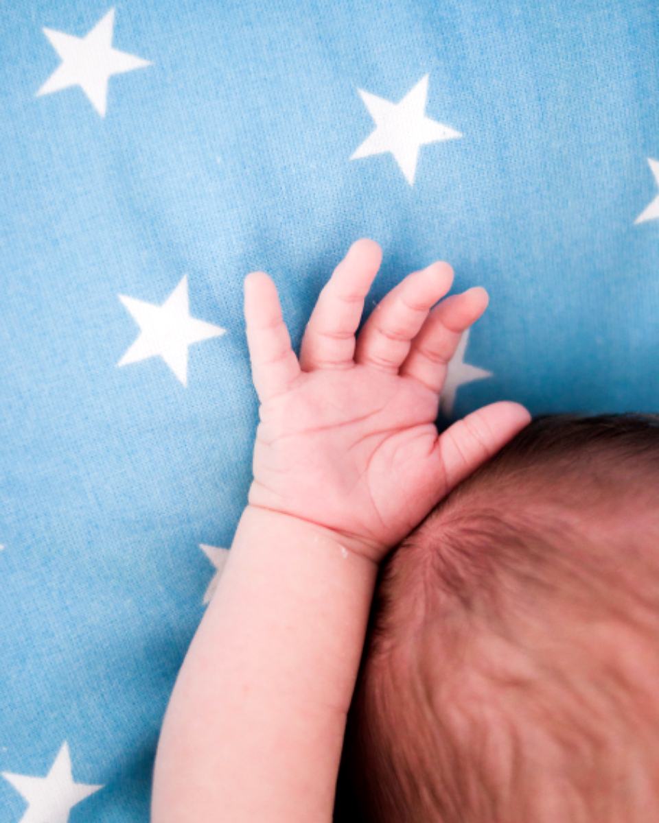 Reference frame: a newborn's hand resting open on a star-patterned blanket