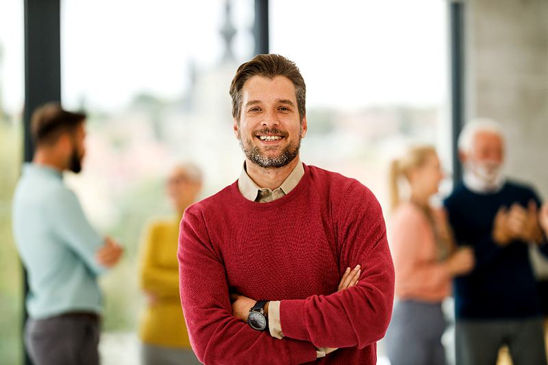 Reference frame: a professional portrait, arms folded, colleagues behind