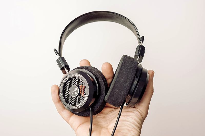 Reference frame: a hand holding headphones against plain white