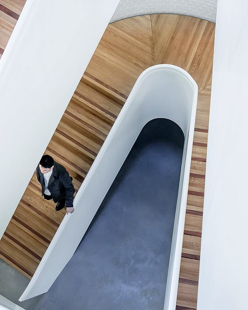 Reference frame: curved stairwell from above with a figure on the landing