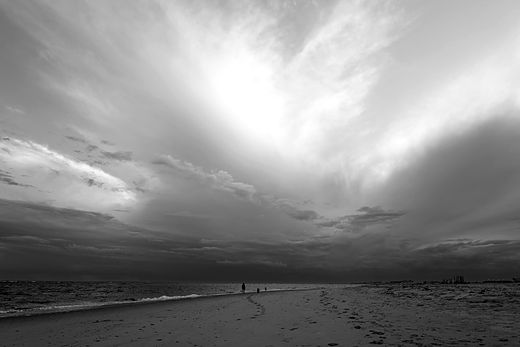 Monochrome cloud burst over a wide empty beach