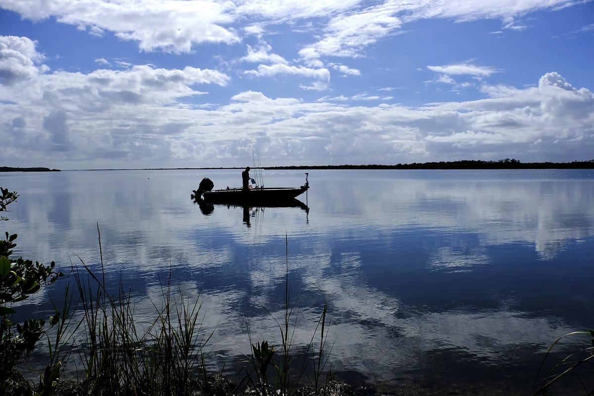 Lone fisherman silhouetted on absolutely still water